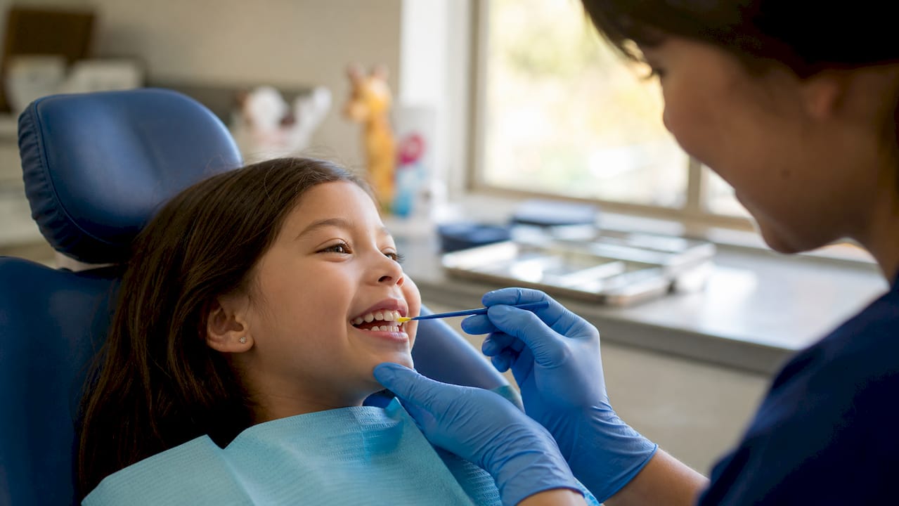 Child receiving fluoride application in dental chair
