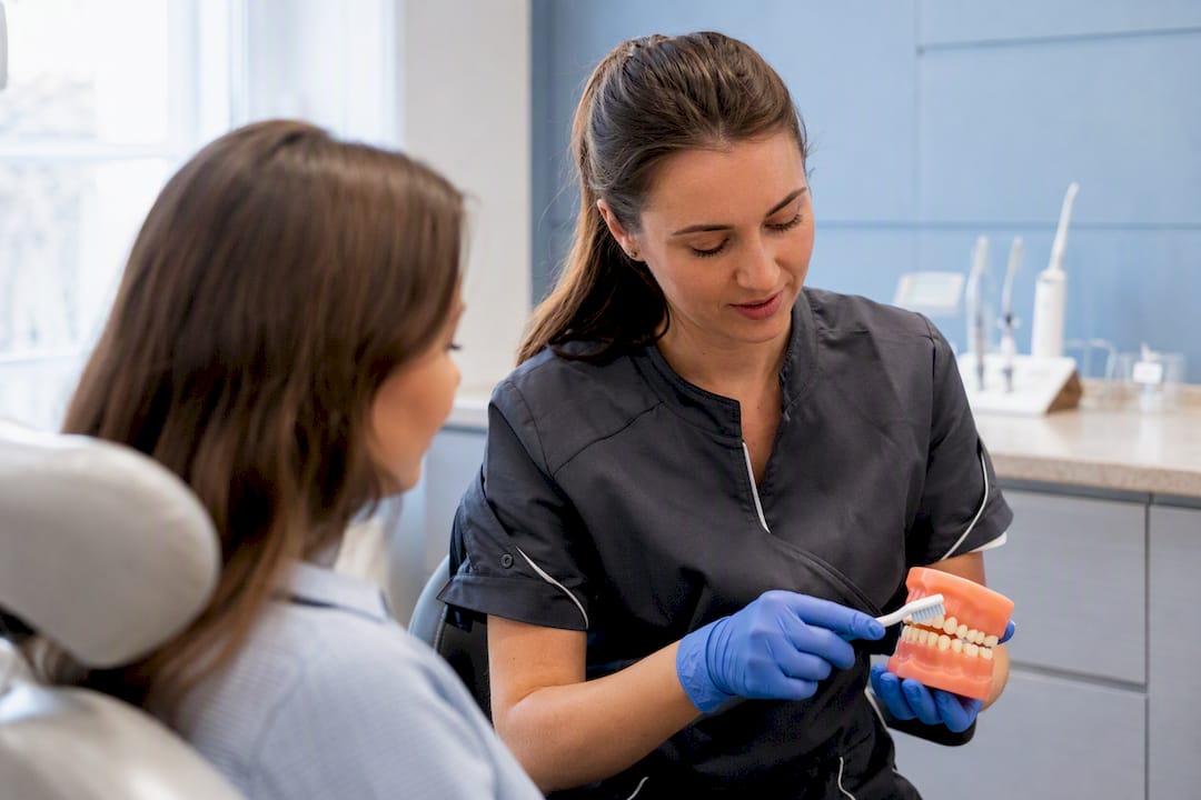 Dental hygienist demonstrating gentle brushing on model