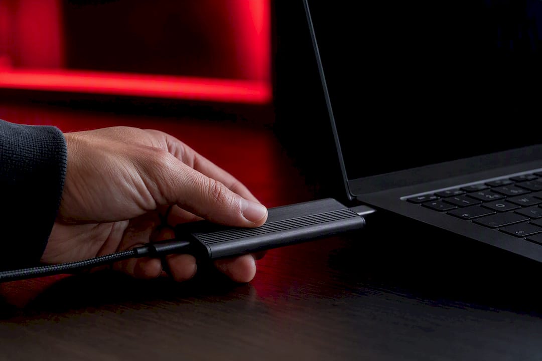 Hand connecting NVMe external SSD to laptop USB-C port