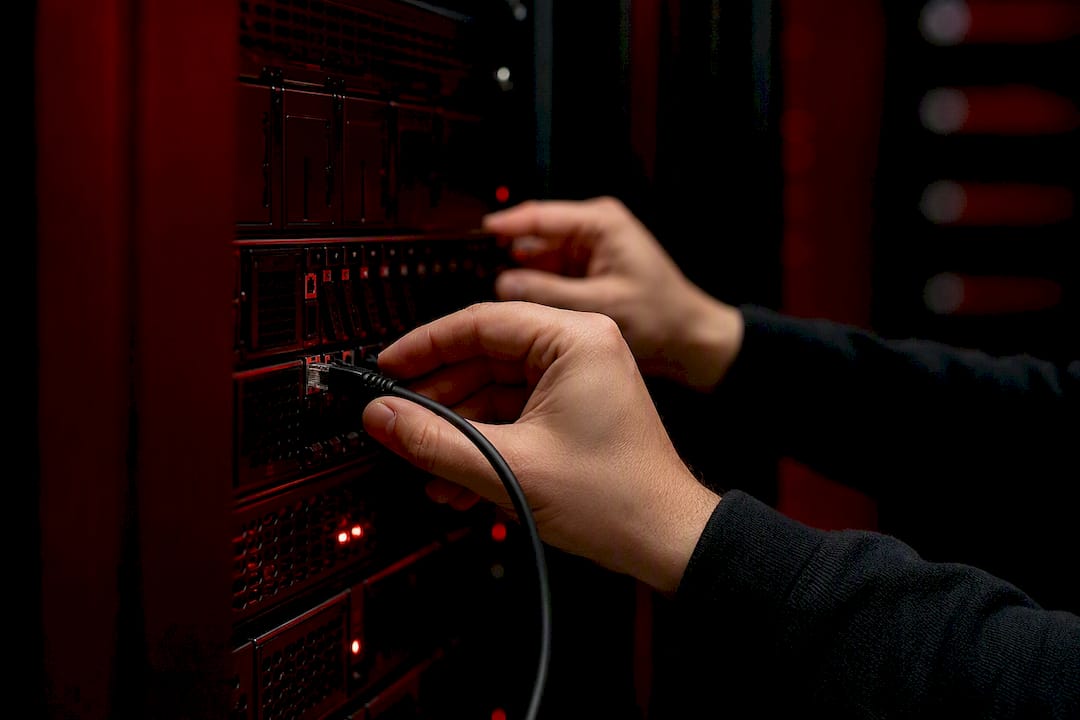Hands connecting network cable to server
