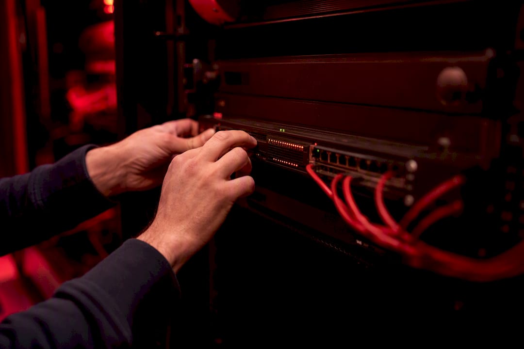 Hands adjusting firewall hardware in server room