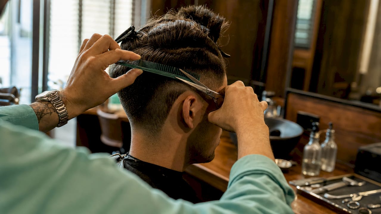 Šikovné ruky barbera vytvárajú tradičný undercut účes
