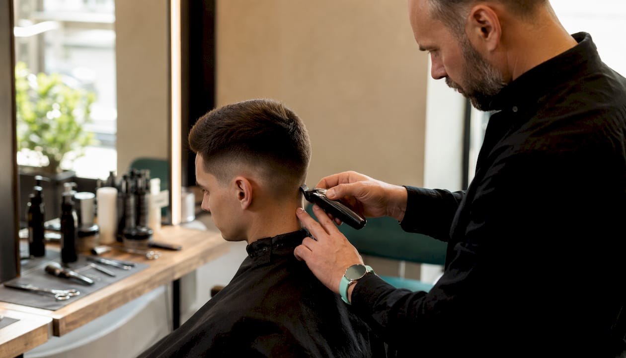 Barber upravuje pánsky účes s precízne vytvarovanými líniami.