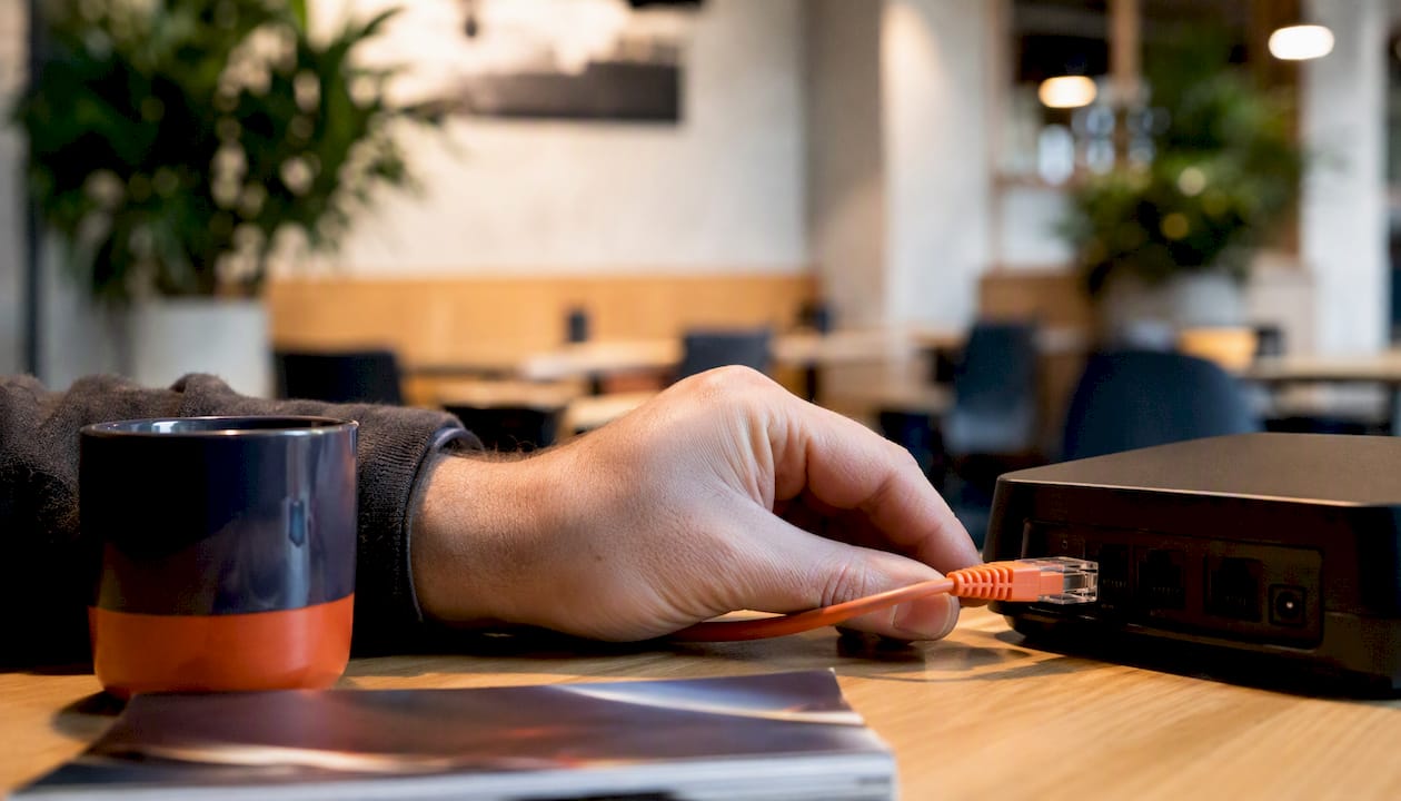 Een hand sluit een kabel aan op een VoIP-adapter.