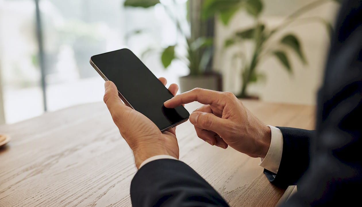 Een hand die op een mobiele telefoon het doorschakelen van oproepen inschakelt.