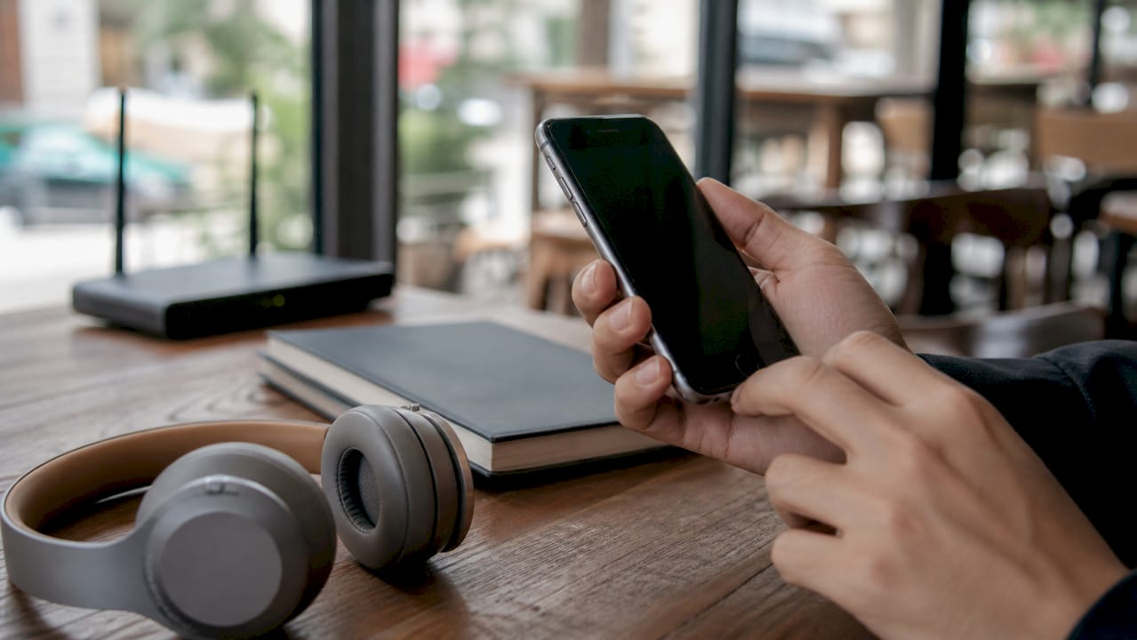 Een hand die een smartphone vasthoudt om een telefoonnummer in te voeren