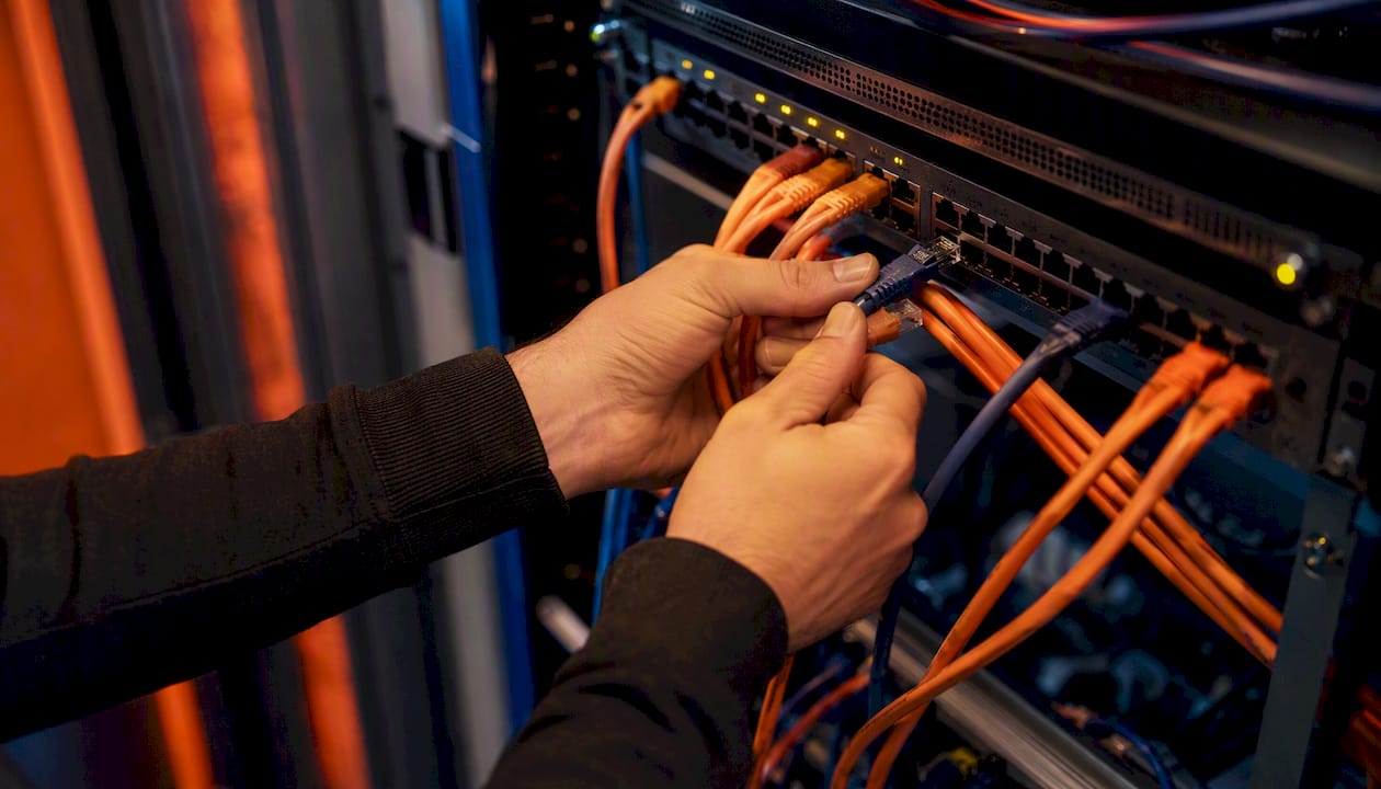 Handen die netwerkkabels aansluiten op een switch