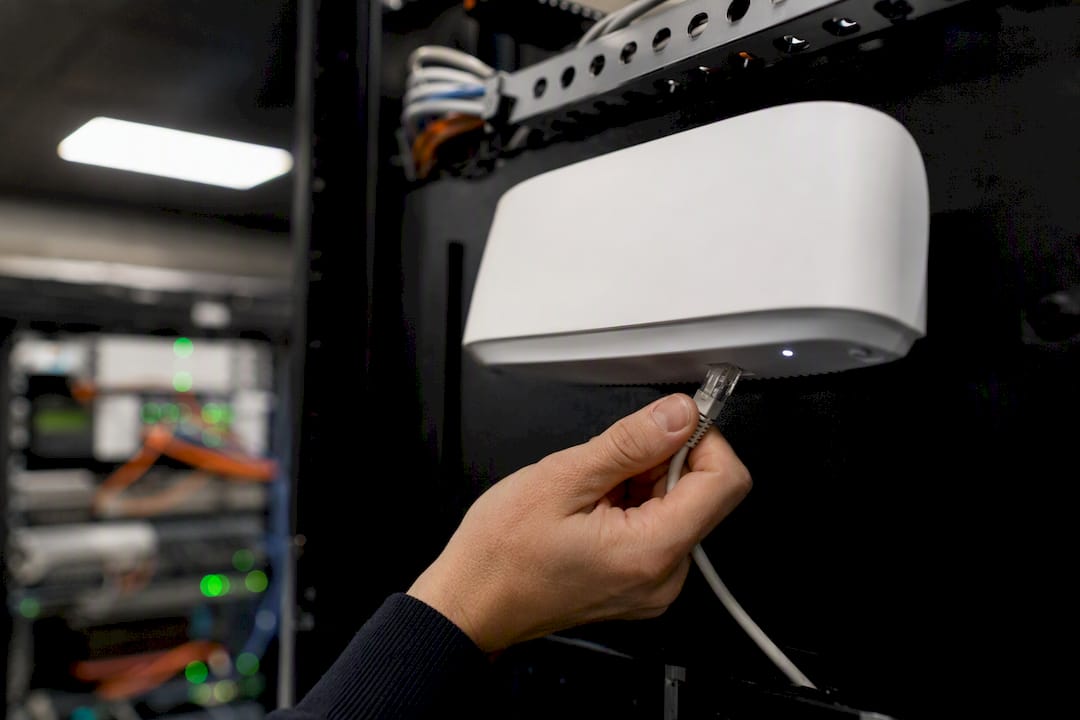Hand die een netwerkkabel aansluit in een serverrack