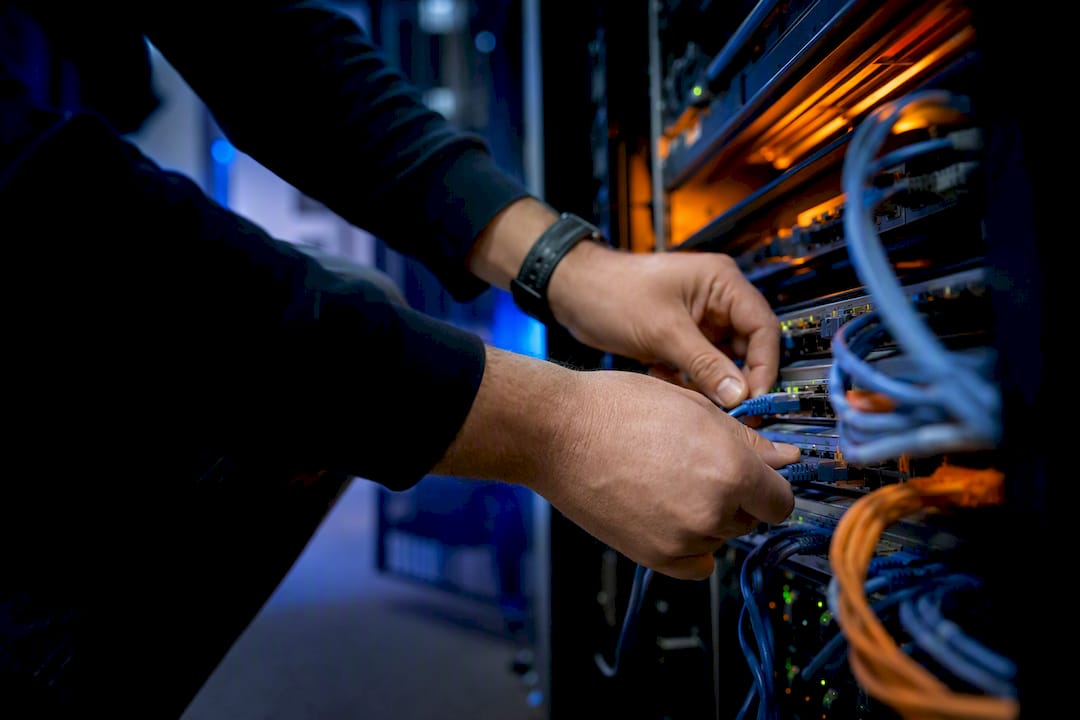 Handen die een netwerkkabel aansluiten in de serverruimte