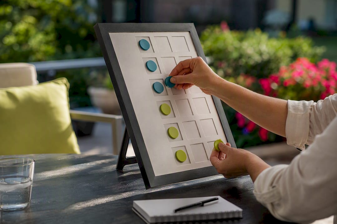 Hands marking franchise coaching checklist with tokens