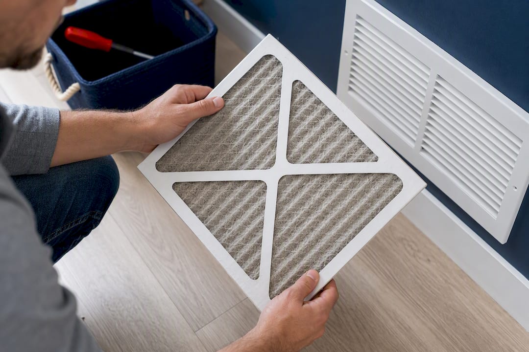 Homeowner examining a dusty AC air filter