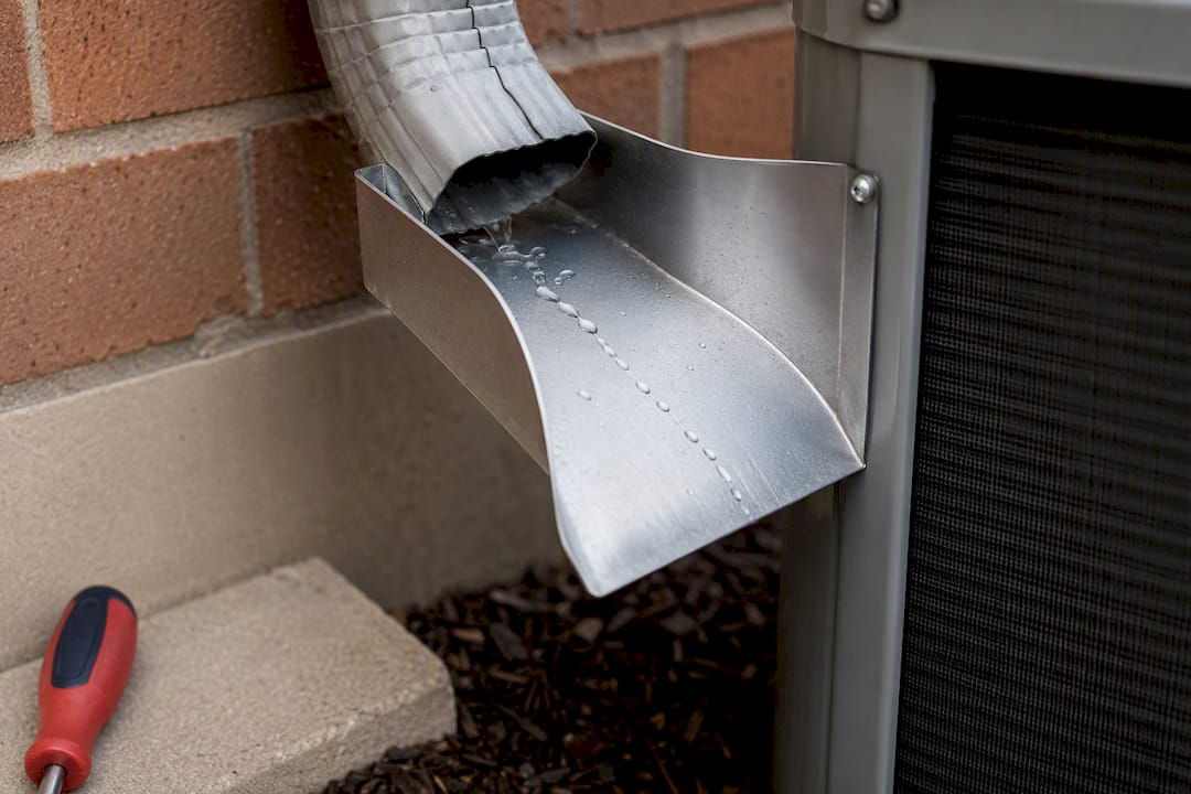 Gutter diverter directing water away from heat pump