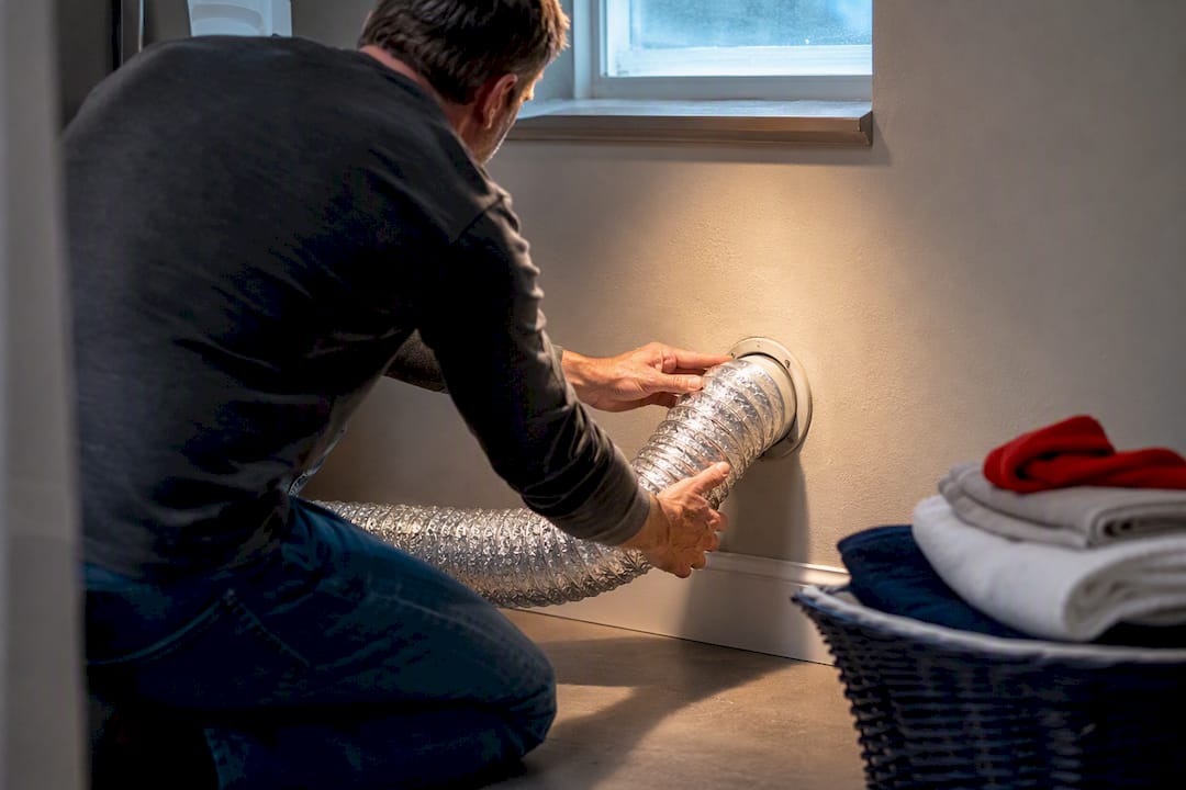 Hands inspecting basement dryer vent hose
