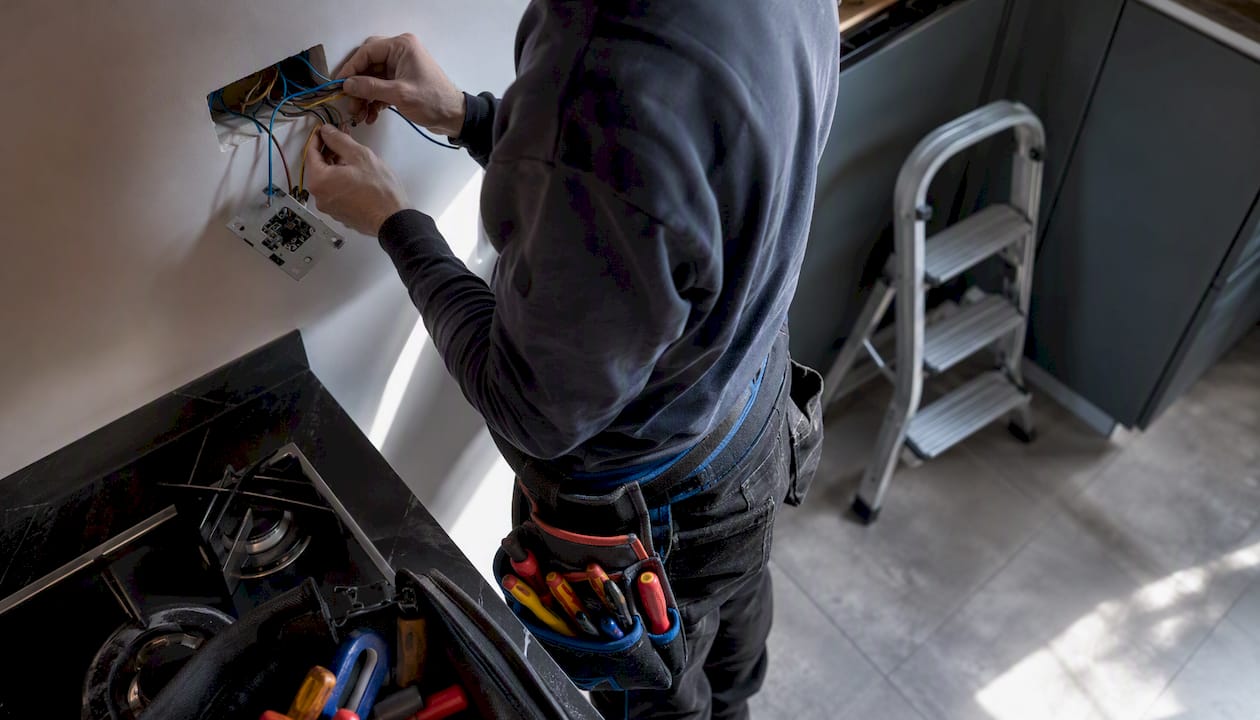 Hands installing electrical wiring in wall
