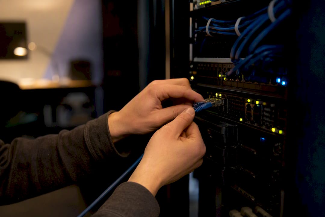 Hands connecting network cable in server room