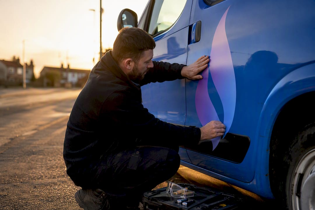 Hands applying flame logo decal on van