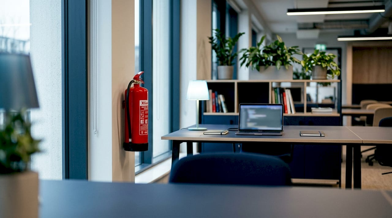 Un extincteur à eau pulvérisée est installé sur le mur du bureau, prêt à être utilisé en cas d'urgence.
