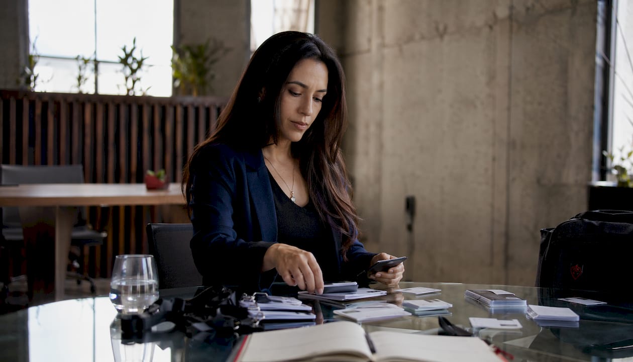 Une femme en train de trier les badges d’accès et de gérer les appareils électroniques.