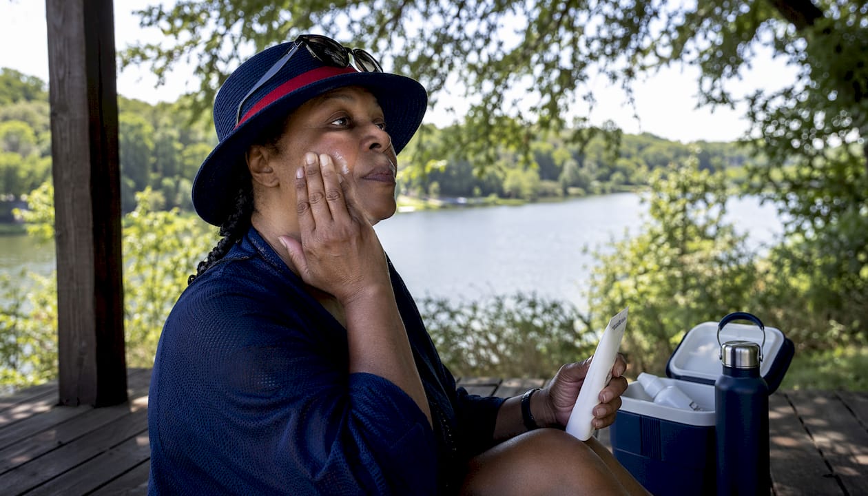 Woman applying mineral sunscreen outdoors at beach