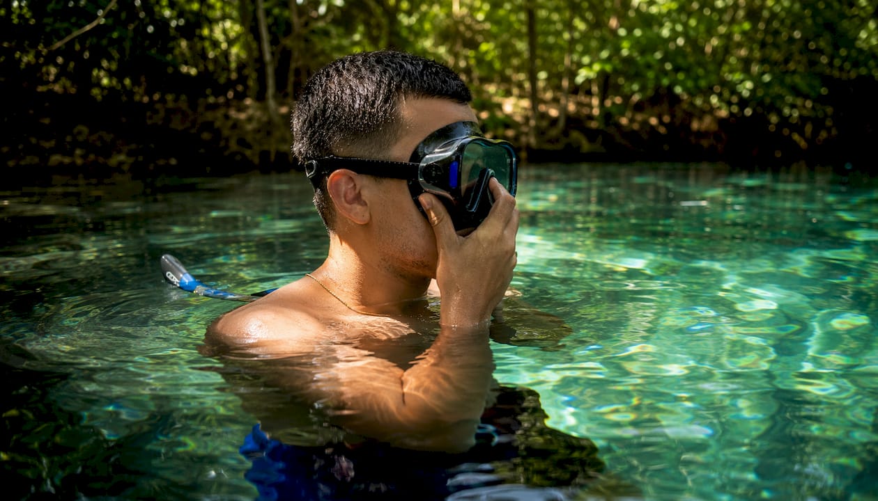 Man testing snorkel mask suction fit at poolside