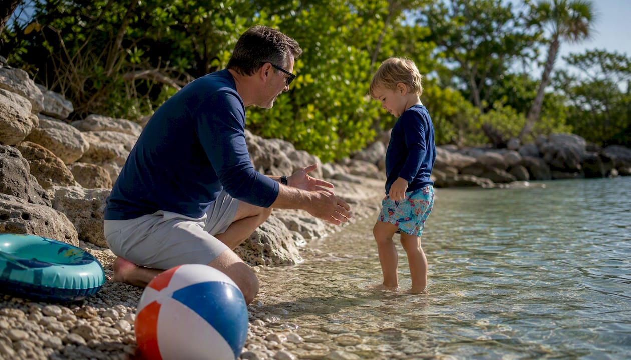 Adult teaching child stingray shuffle at beach