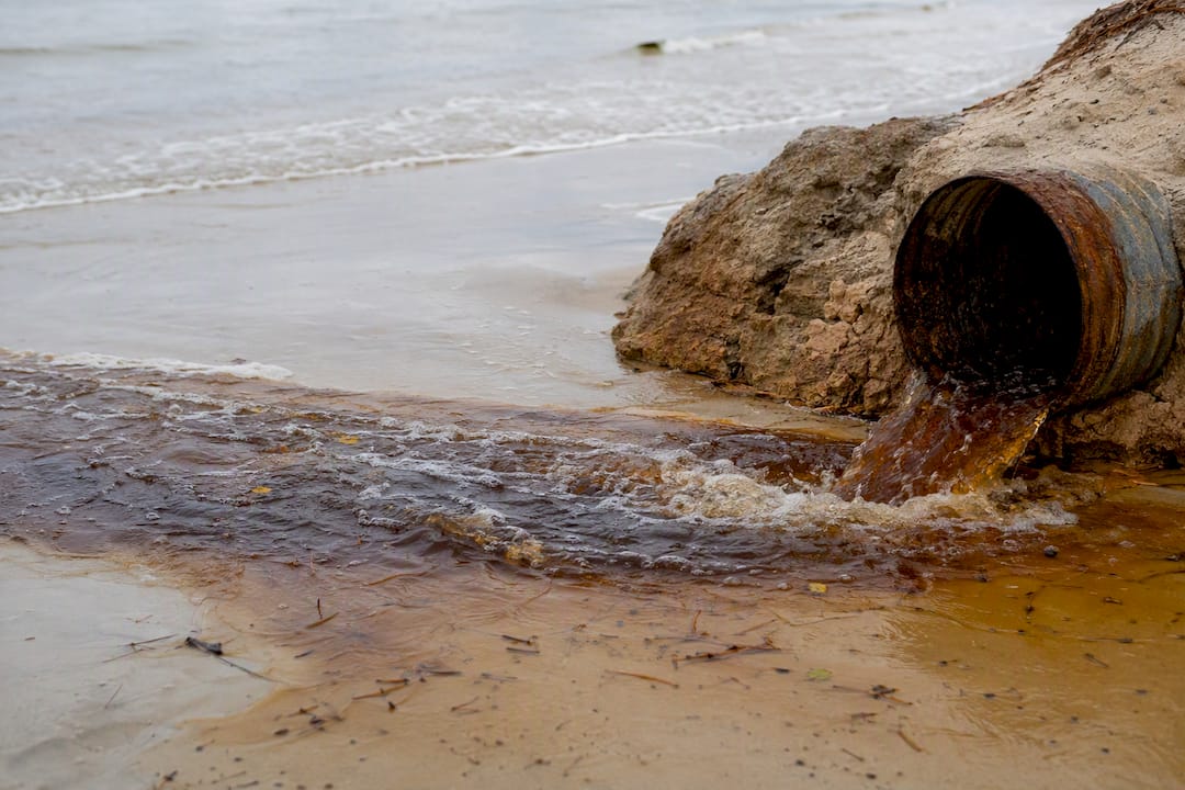 Brown tannin-stained water flowing from beach outfall