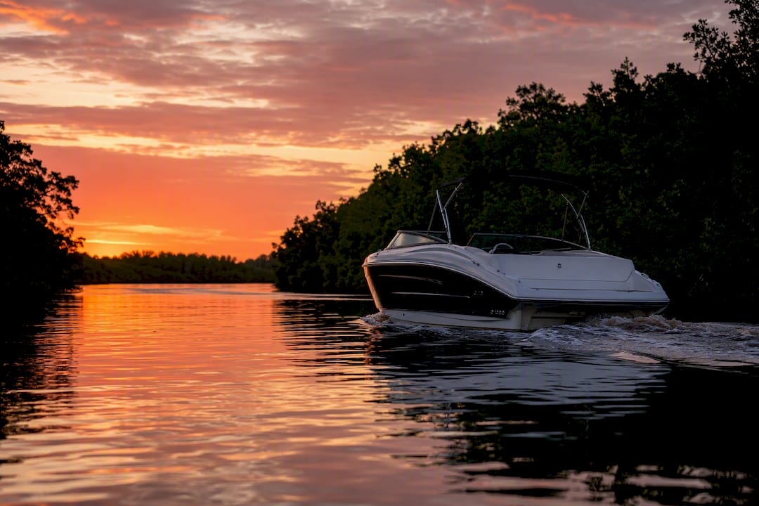 Powerboat cruising tidal channel at sunset
