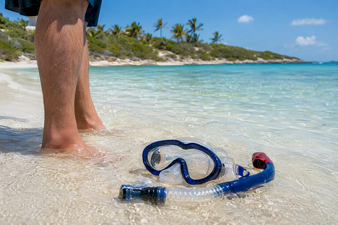Snorkel gear in ankle-deep water with feet