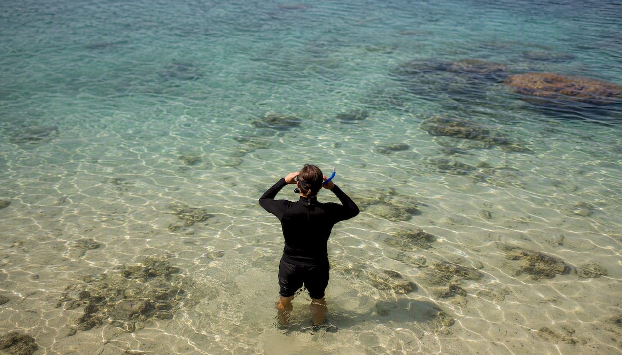 Snorkeler standing in shallow water near shore