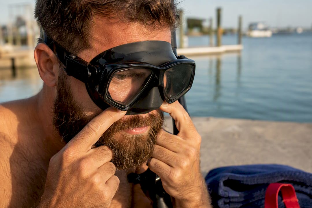 Bearded snorkeler checking mask seal