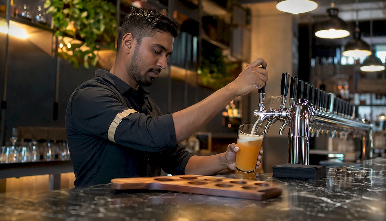Bartender pouring beer from keg tap at bar