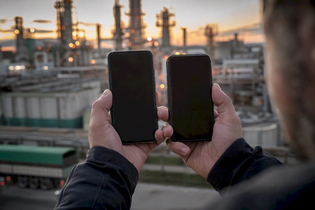 Technician holding two dark smartphones outdoors