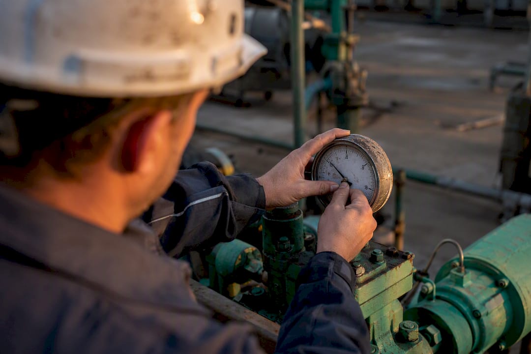 Technician adjusting industrial pressure gauge