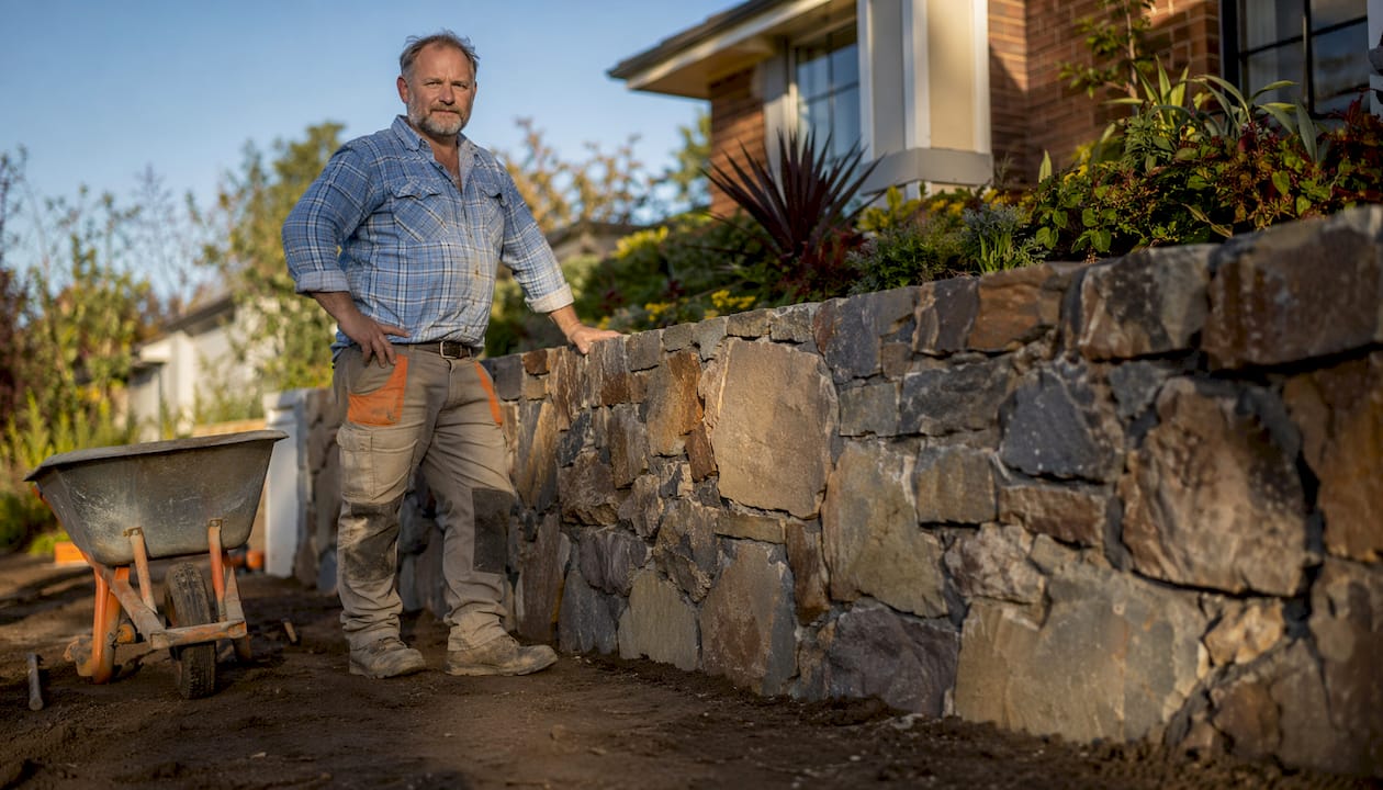 Licensed builder near finished rock retaining wall