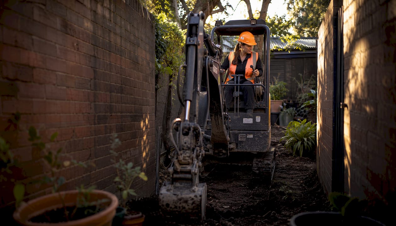 Compact excavator in narrow backyard