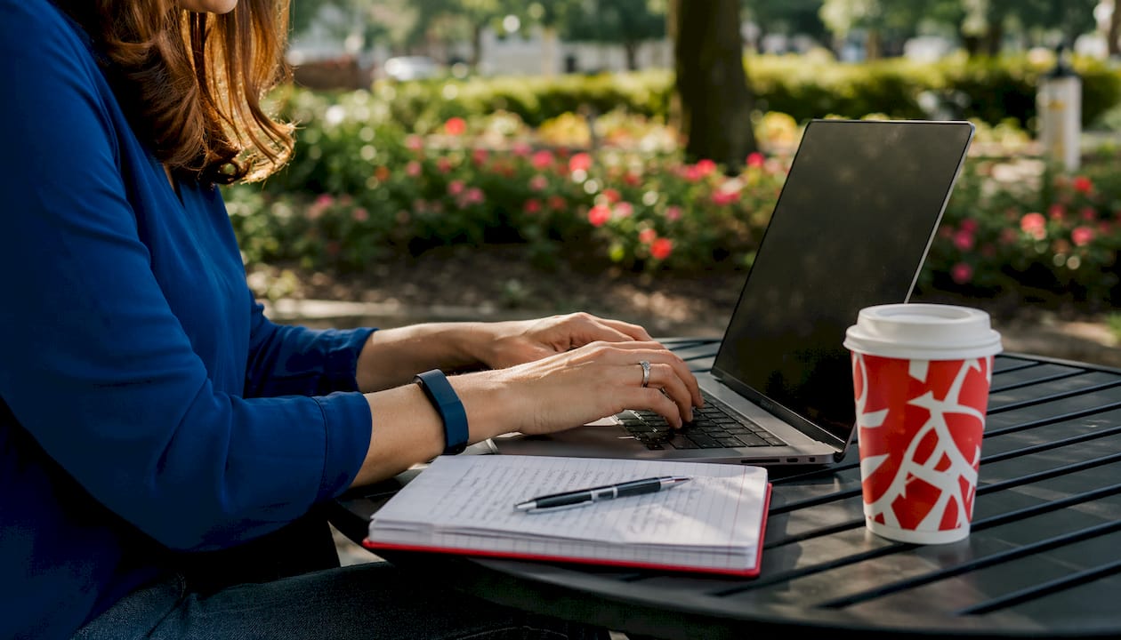 Hands typing laptop with marketing notes and coffee