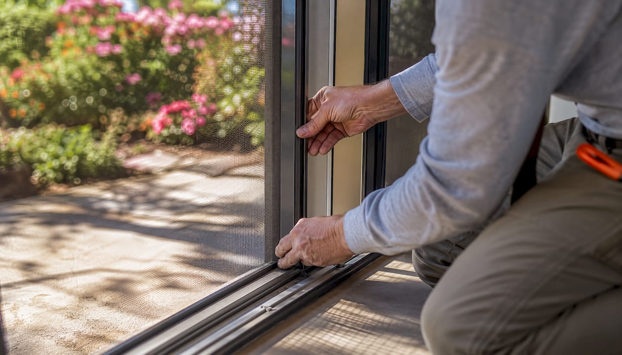 Installer fitting insect-proof mesh into door frame