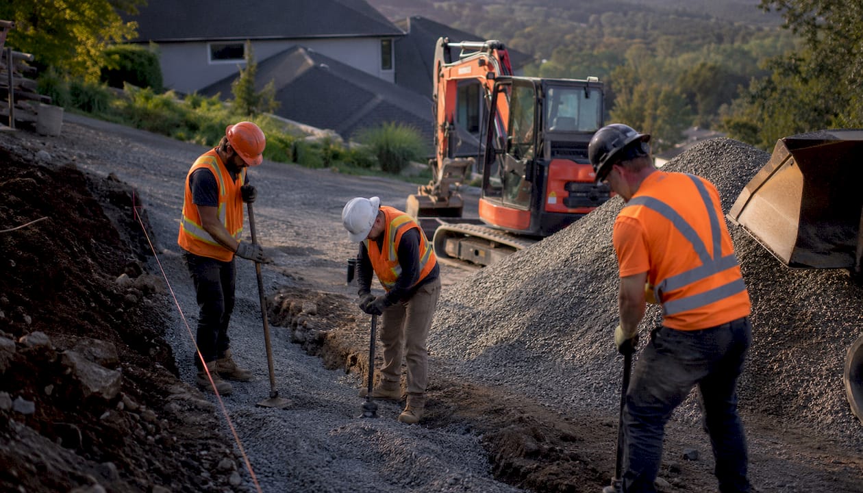 Contractors preparing driveway wall foundation trench