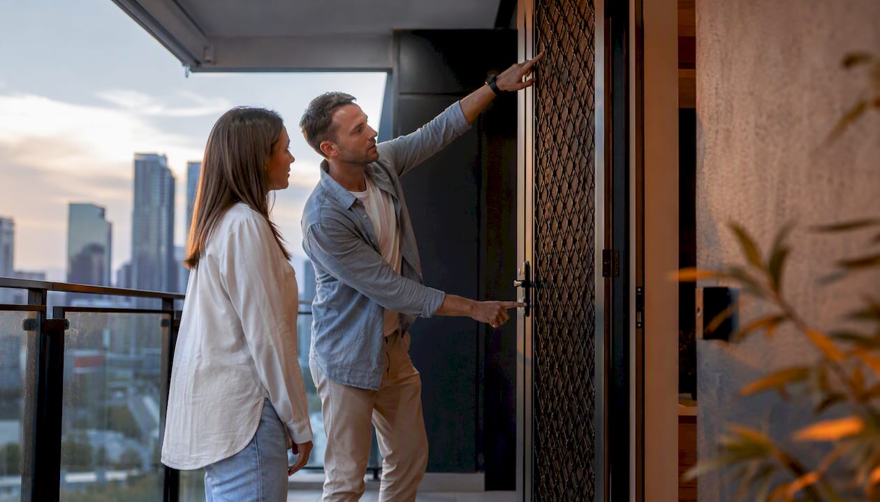 Couple inspecting triple lock security door outdoors