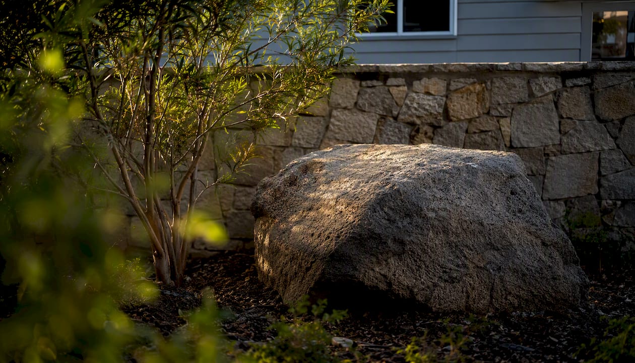 Large boulder contrasted with courtyard wall for scale