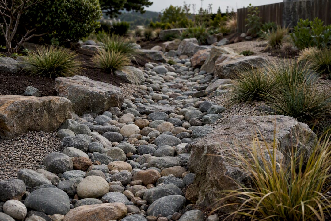 Dry creek bed carrying drainage through rock garden