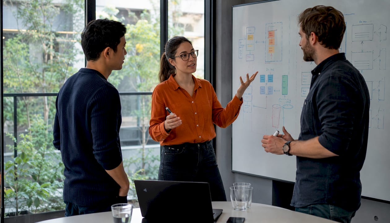 Ein Team erarbeitet gemeinsam am Whiteboard ein Konzept für eine Microservices-Architektur.
