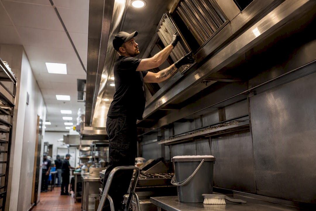 Hands removing commercial kitchen grease filter