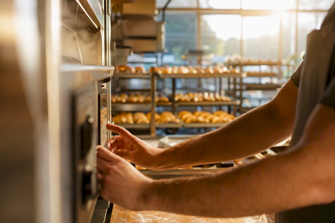 Hands adjusting commercial oven controls in bakery