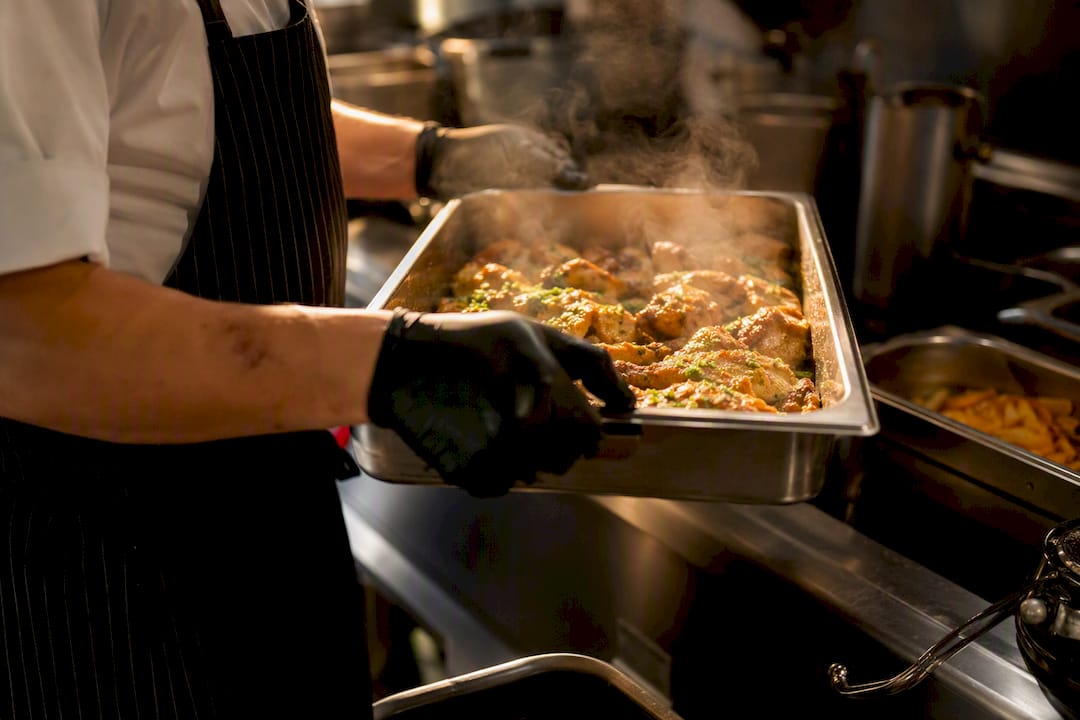 Chef lifting hot gastronorm pan above shoulder height