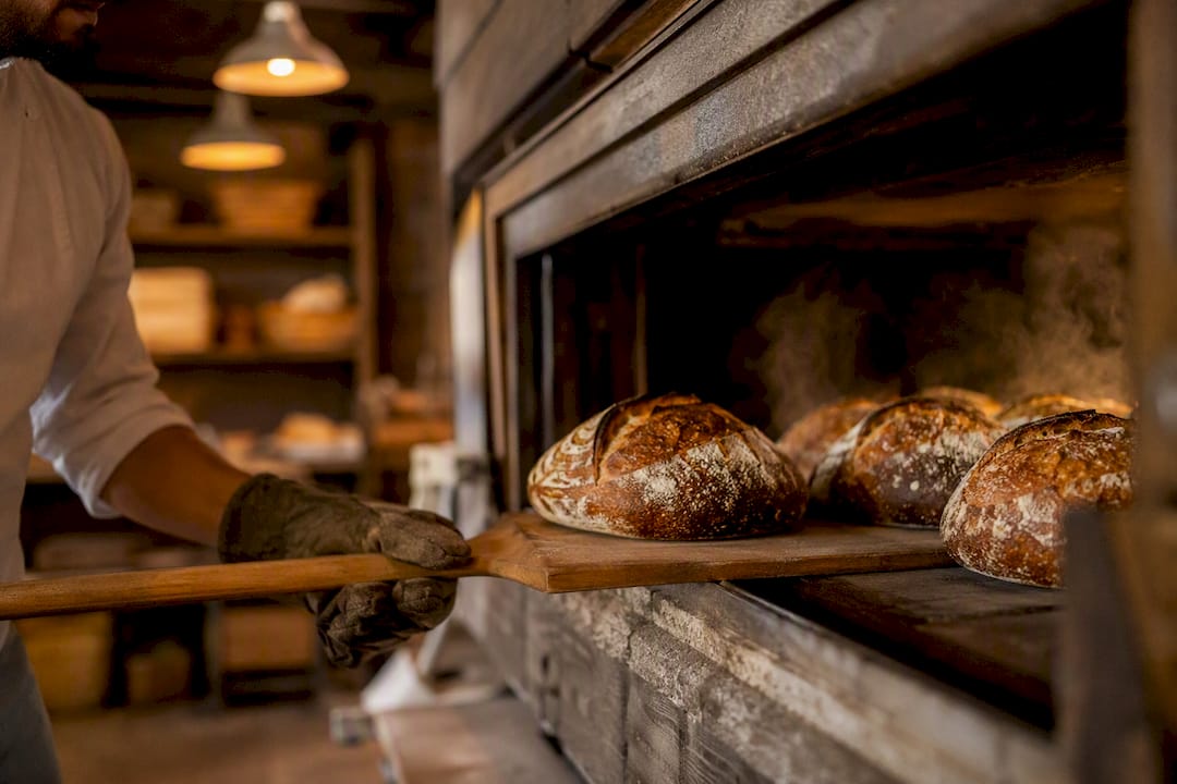 Baker sliding sourdough into deck oven