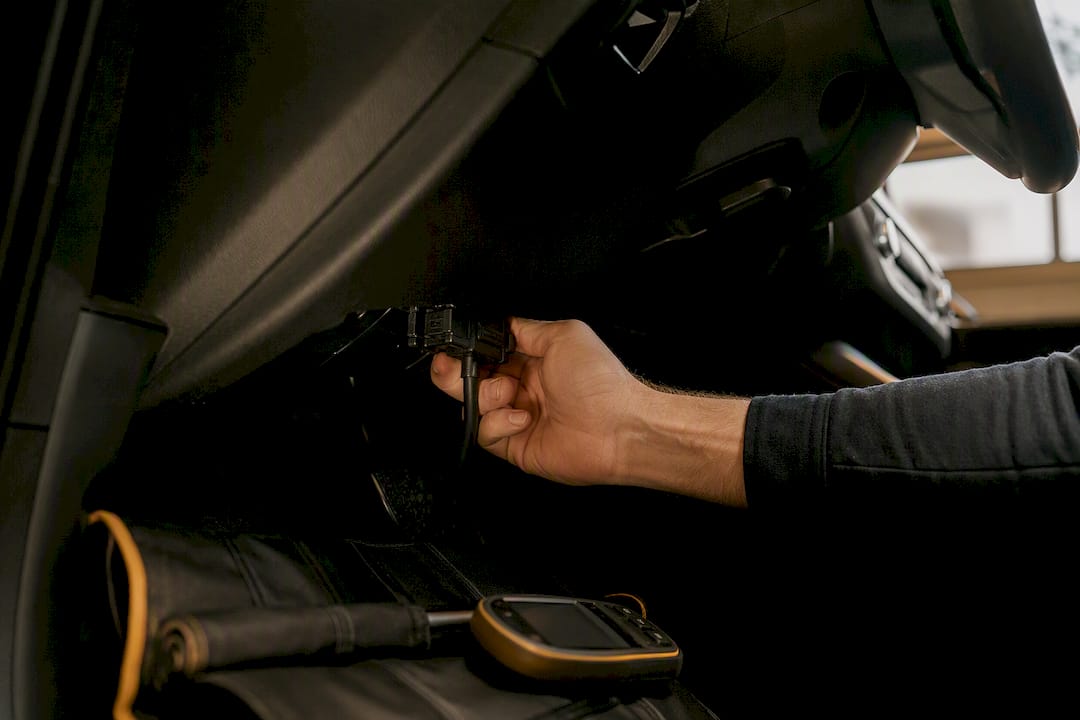 Hand connecting OBD2 scanner in car