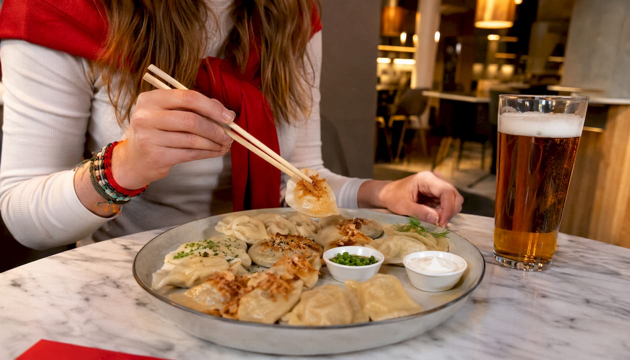 Hands reaching platter with assorted pierogi