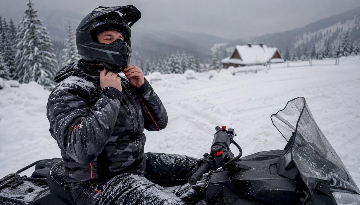 Snowmobile rider preparing at snowy mountain lodge