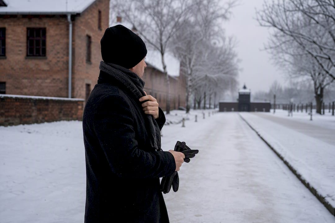 Visitor layering warm coat outdoors at snowy memorial